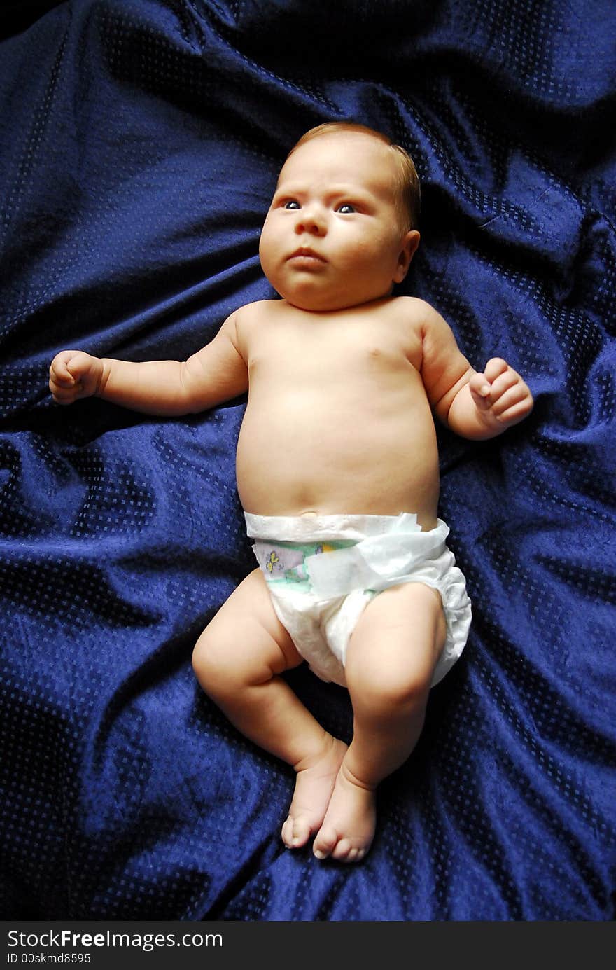 A small baby lying on a blue sheet. A small baby lying on a blue sheet