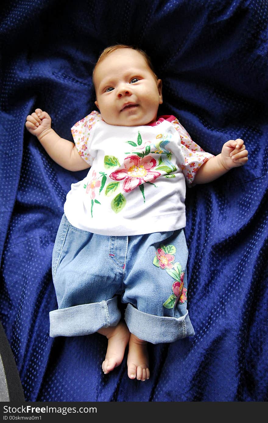 A small baby lying on a blue sheet. A small baby lying on a blue sheet