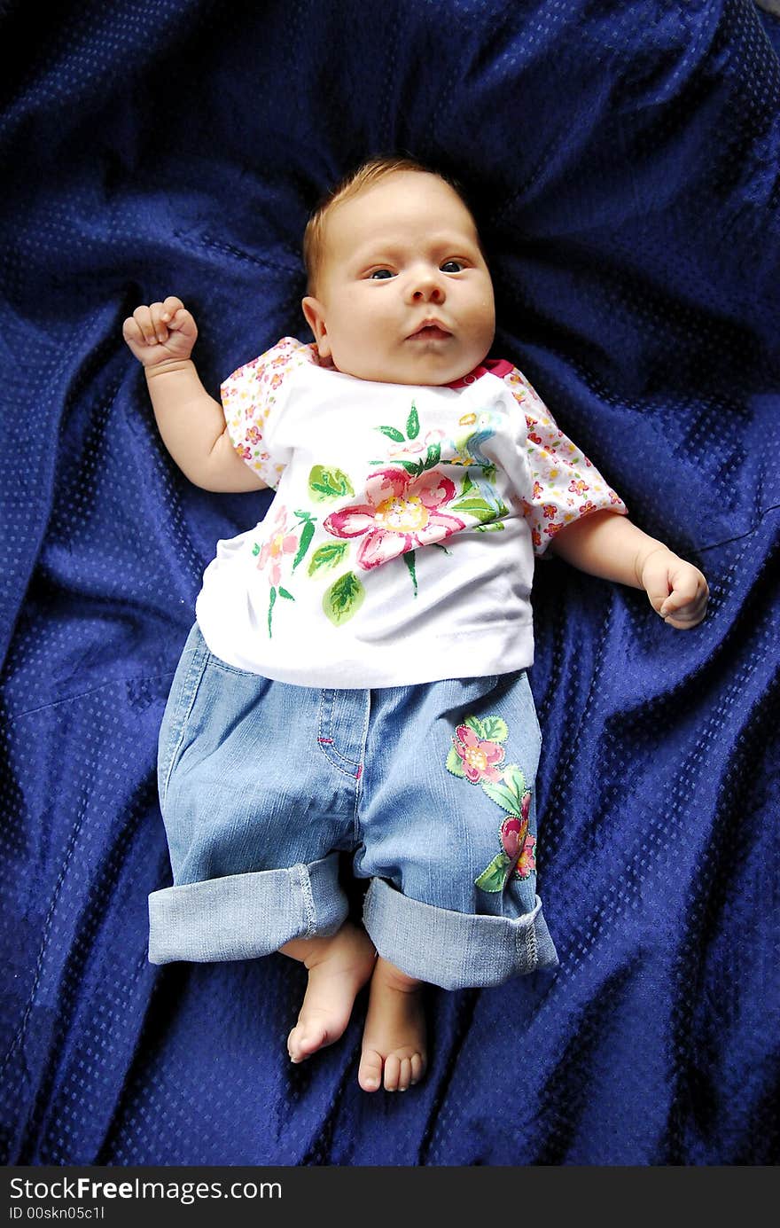 A small baby lying on a blue sheet. A small baby lying on a blue sheet