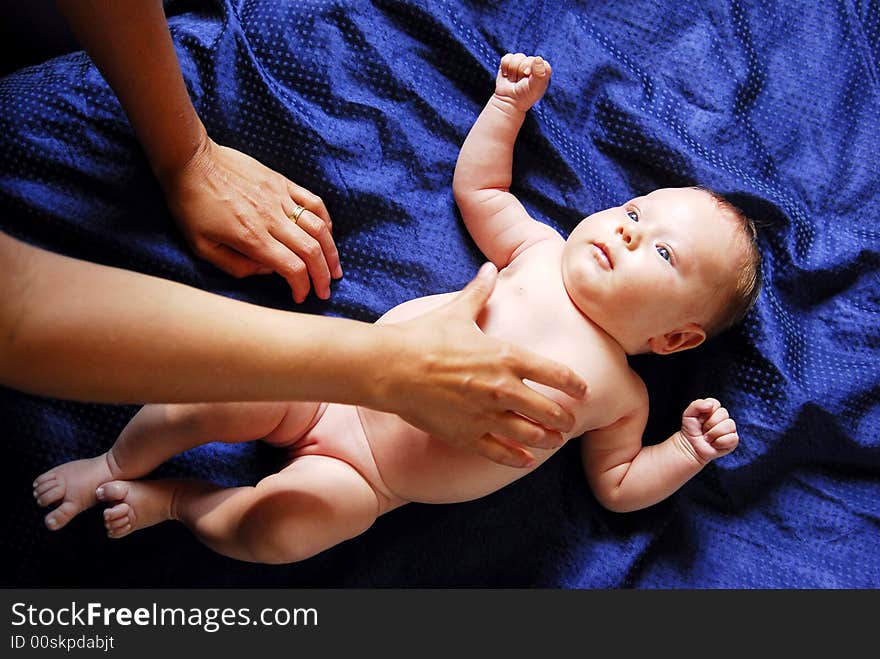 A small baby lying on a blue sheet. A small baby lying on a blue sheet