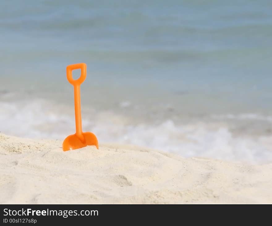 Red plastic spade on the sunny tropical beach