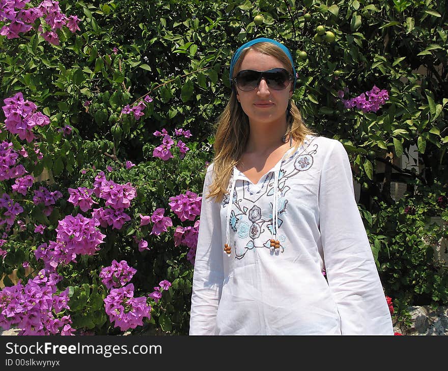 There is a beautiful girl next to the bush of bougainvillea. There is a beautiful girl next to the bush of bougainvillea