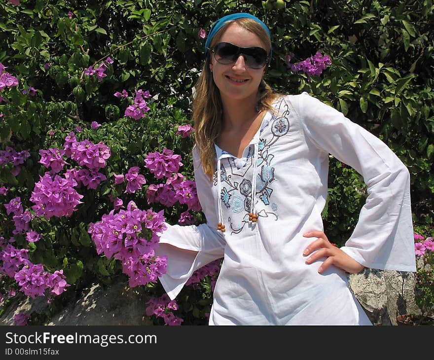 There is a beautiful girl next to the bush of bougainvillea. There is a beautiful girl next to the bush of bougainvillea