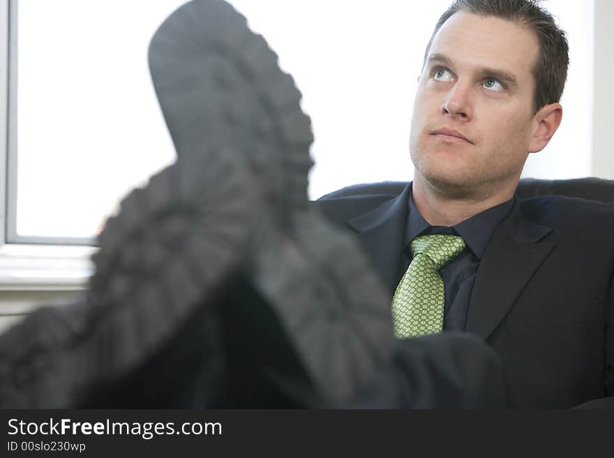 A business man sits in his office with his feet on his desk thinking of his next big project. A business man sits in his office with his feet on his desk thinking of his next big project