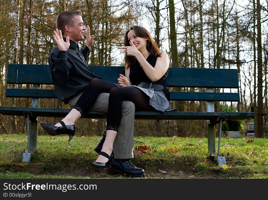 Man and girlfriend on a bench in a park having fun. Man and girlfriend on a bench in a park having fun