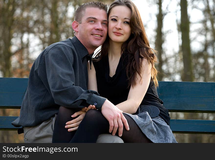 Man and girlfriend on a bench in a park showing their love. Man and girlfriend on a bench in a park showing their love