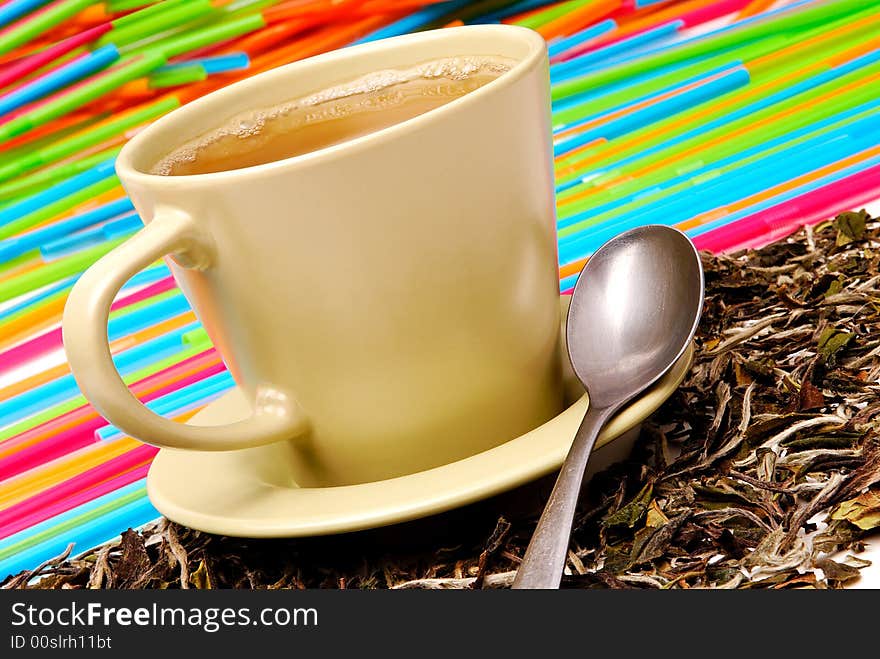 Cup of the green tea with spoon and leaves of tea around