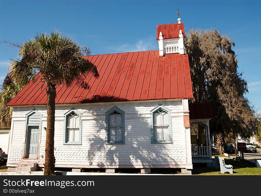 An old church building downtown with spanish moss growing off a nearby tree.