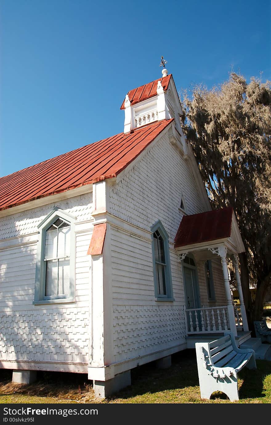 An old church building downtown with spanish moss growing off a nearby tree.