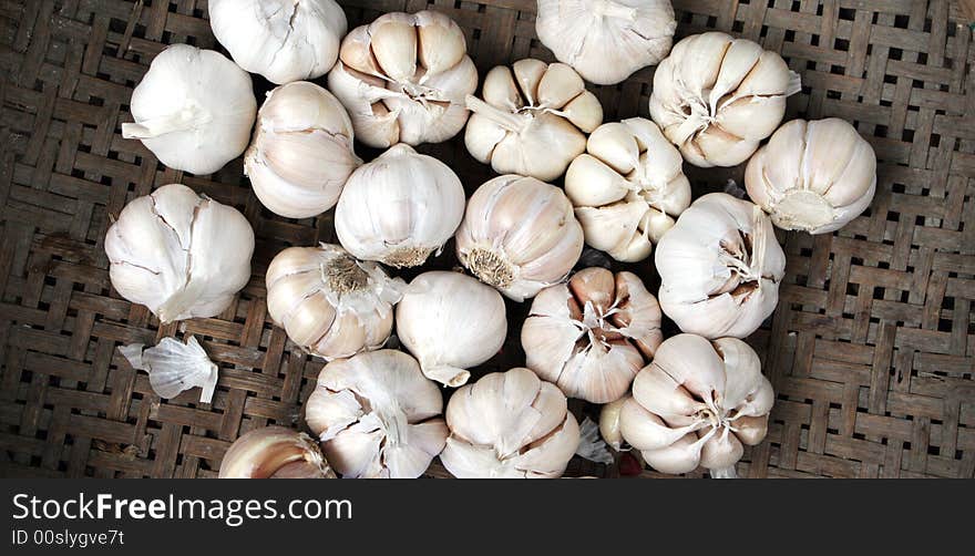 Whole cloves of garlic in a woven cane basket.