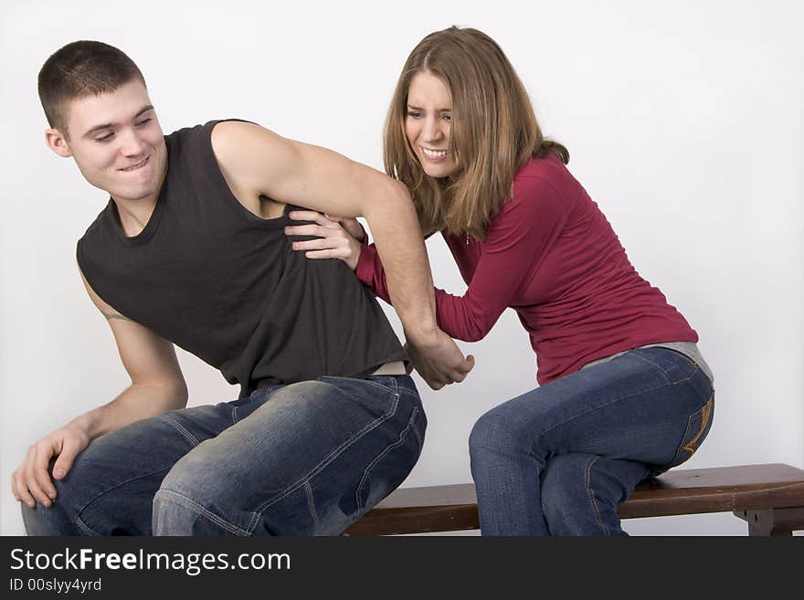 Young couple sitting on a bench wrestling. Young couple sitting on a bench wrestling