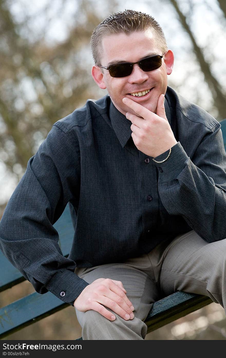 Young man is sitting on a bench in a park. Young man is sitting on a bench in a park