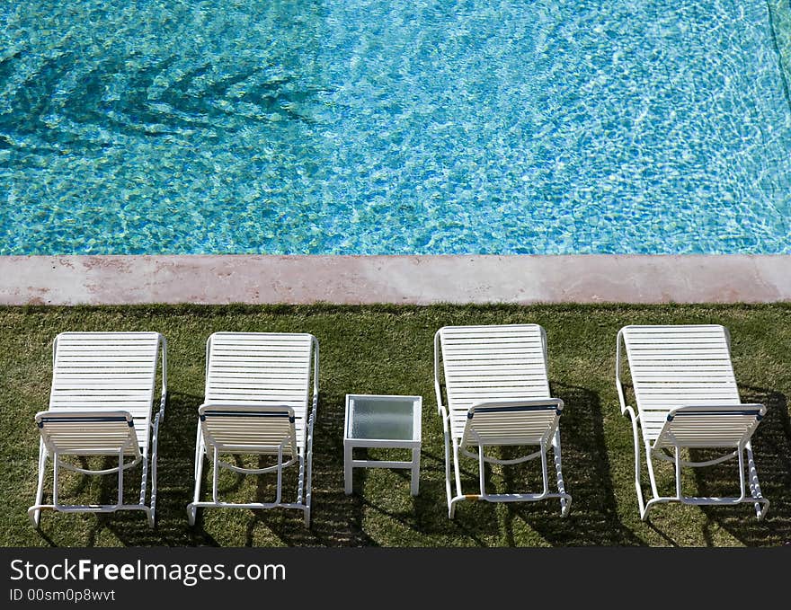 Ready for you -- a row of white lounge chairs by a resort pool. Ready for you -- a row of white lounge chairs by a resort pool.