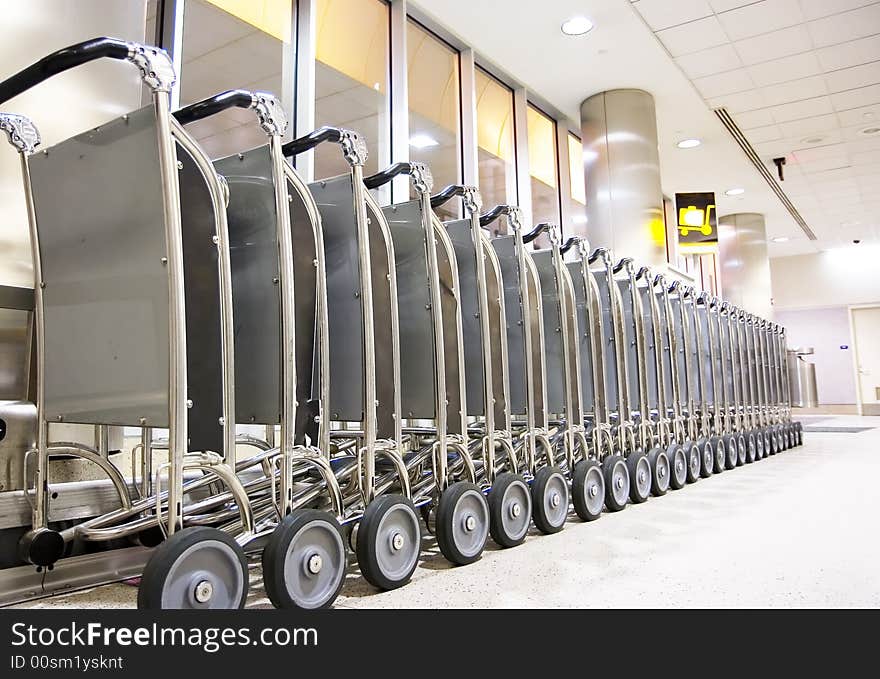 Row of luggage carts at busy airport, with selective focus on the closer carts.