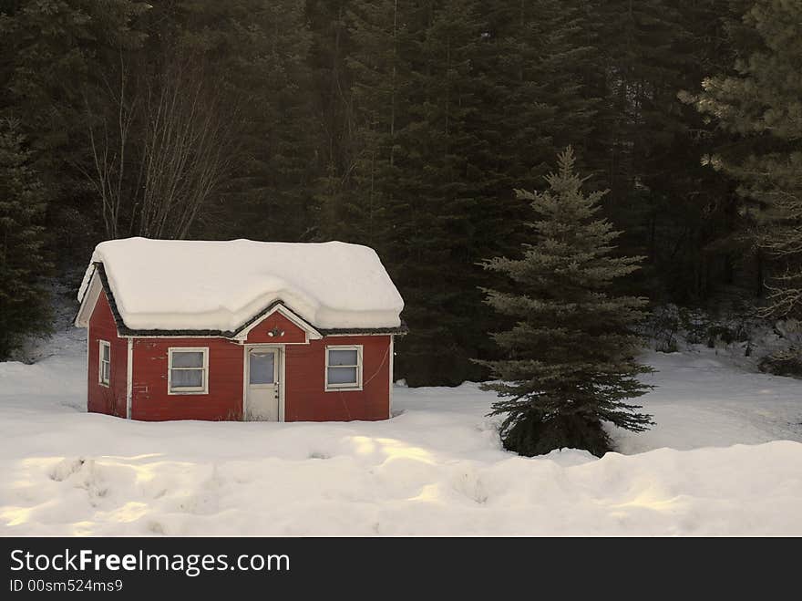 Heavy winter snow covering old red house in forrest. Heavy winter snow covering old red house in forrest