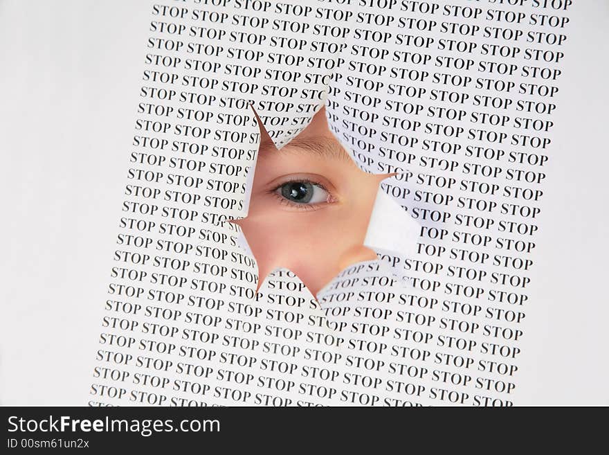 Eye looks into the hole in the sheet of paper with the printed word stop