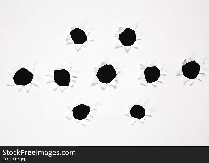 The sheet of paper with the group of holes against the black background