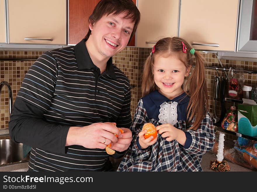 Father and daughter with mandarins on the kitchen