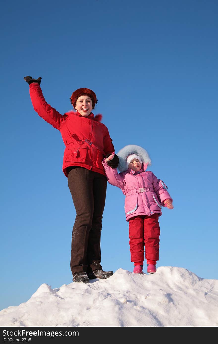 Mother and child stand on top of snowy hill