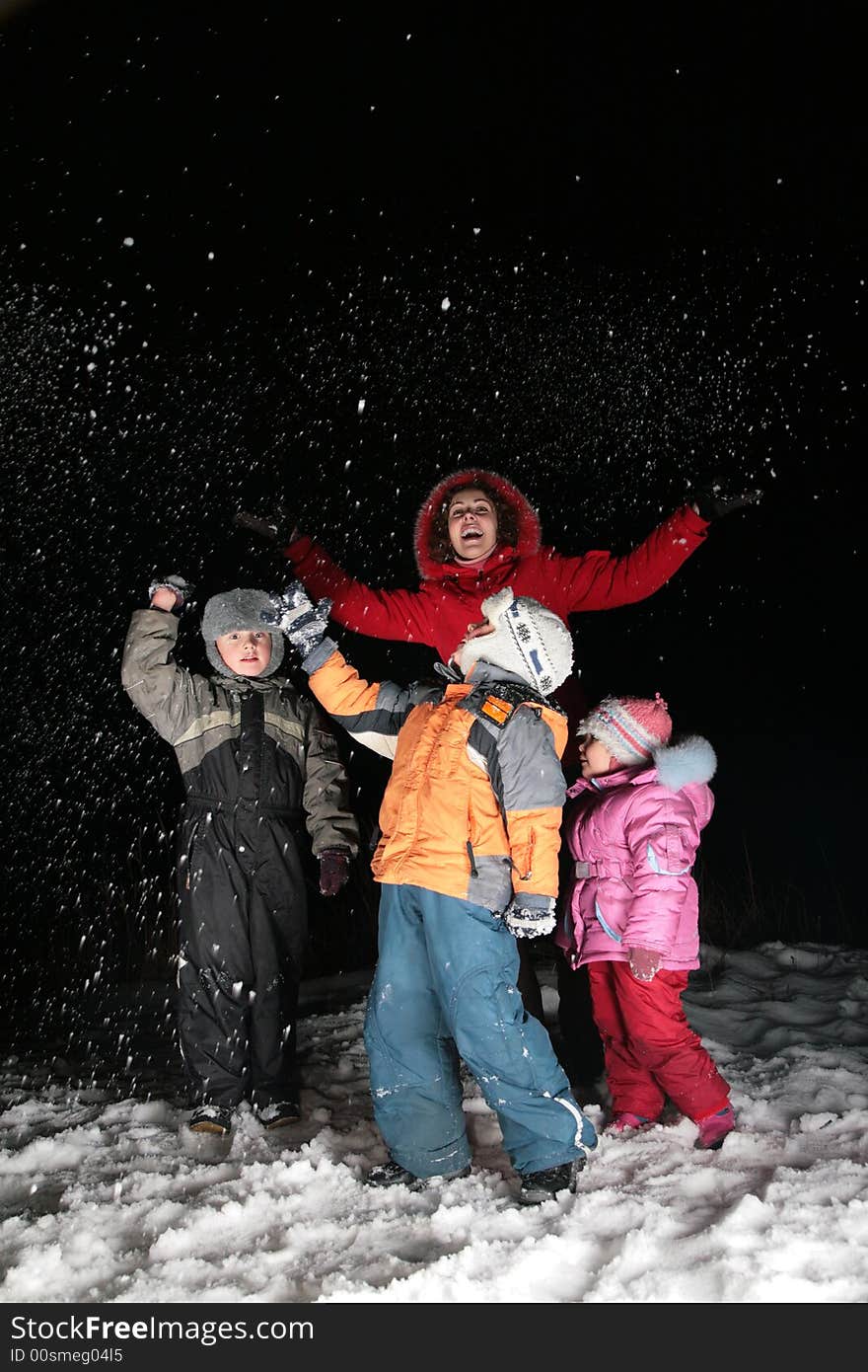 Children and mother throw snow in night