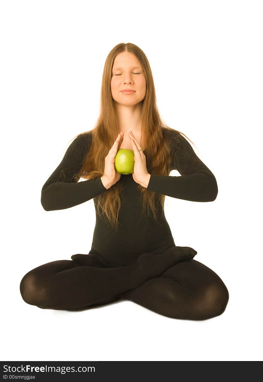 The portrait of a woman in lotus pose with a green apple in her hands. The portrait of a woman in lotus pose with a green apple in her hands