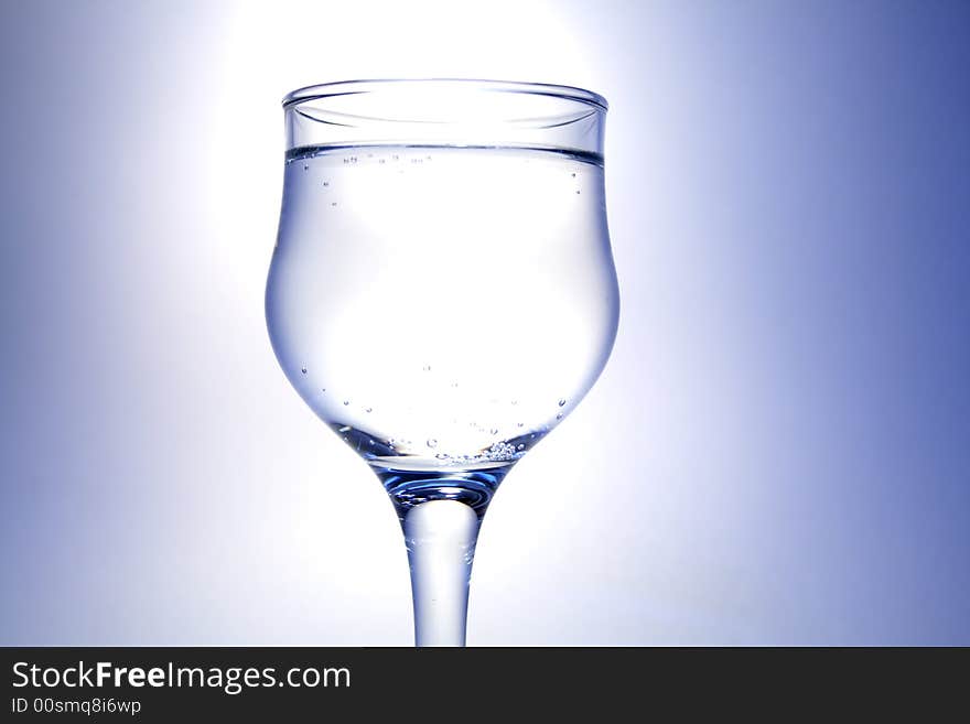 Nice goblet with light drink and blebs standing on white-blue background. Nice goblet with light drink and blebs standing on white-blue background