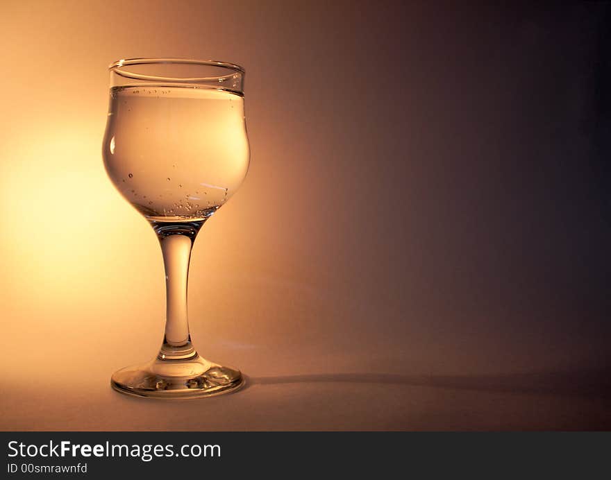 Nice goblet of champagne with blebs standing on golden background. Nice goblet of champagne with blebs standing on golden background