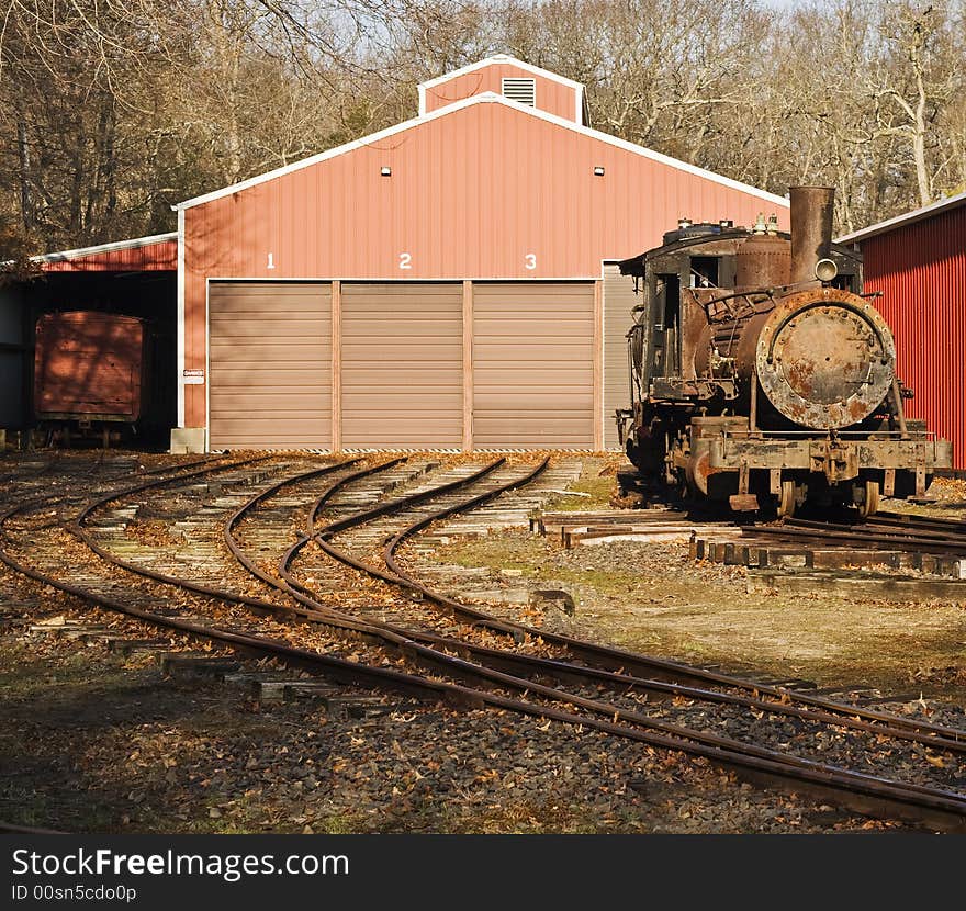 Old rusted locomotive on tracks outside depot