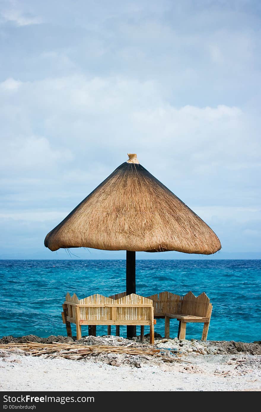 Relaxing native style cabanas on a white sand tropical beach beside the ocean of Caribbean blue water with white foamy waves crashing. Relaxing native style cabanas on a white sand tropical beach beside the ocean of Caribbean blue water with white foamy waves crashing