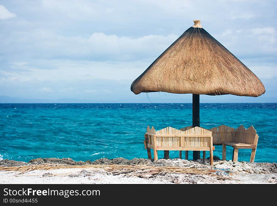 Relaxing native style cabanas on a white sand tropical beach beside the ocean of Caribbean blue water with white foamy waves crashing. Relaxing native style cabanas on a white sand tropical beach beside the ocean of Caribbean blue water with white foamy waves crashing