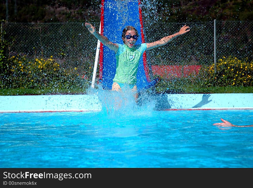 Action shot of girl sliding into swimming pool. Action shot of girl sliding into swimming pool