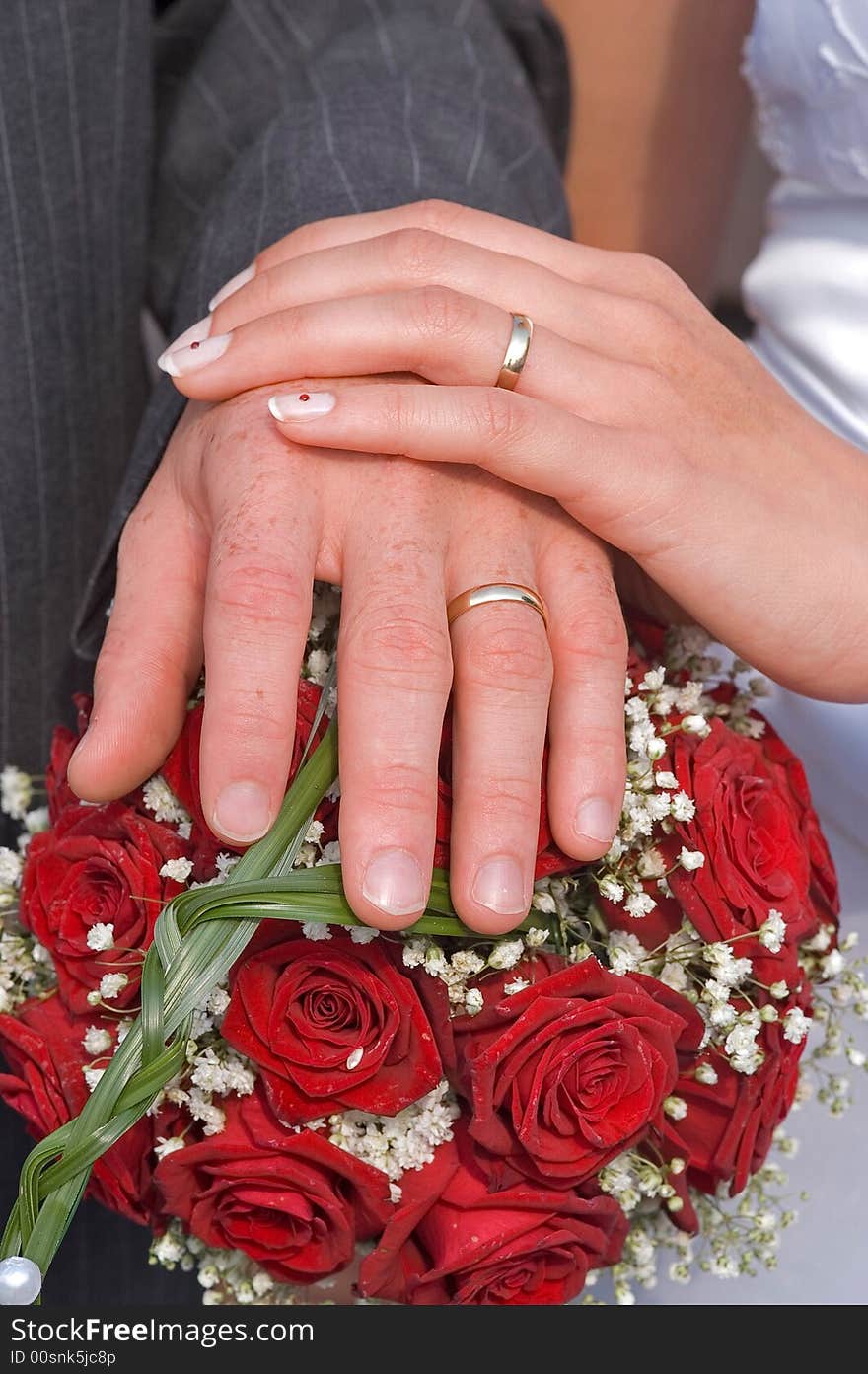 Brides and grooms hands on a bouquet, showing their wedding rings. Brides and grooms hands on a bouquet, showing their wedding rings.