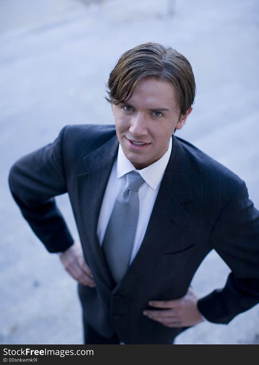 High-angle view of young white businessman standing wearing suit looking up at cameraman. High-angle view of young white businessman standing wearing suit looking up at cameraman