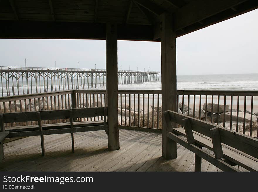 Covered deck seating at the beach with a view of the ocean and pier. Covered deck seating at the beach with a view of the ocean and pier.