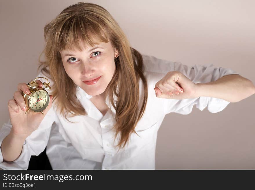 A nice girl in a white shirt holding an alarm-clock. A nice girl in a white shirt holding an alarm-clock