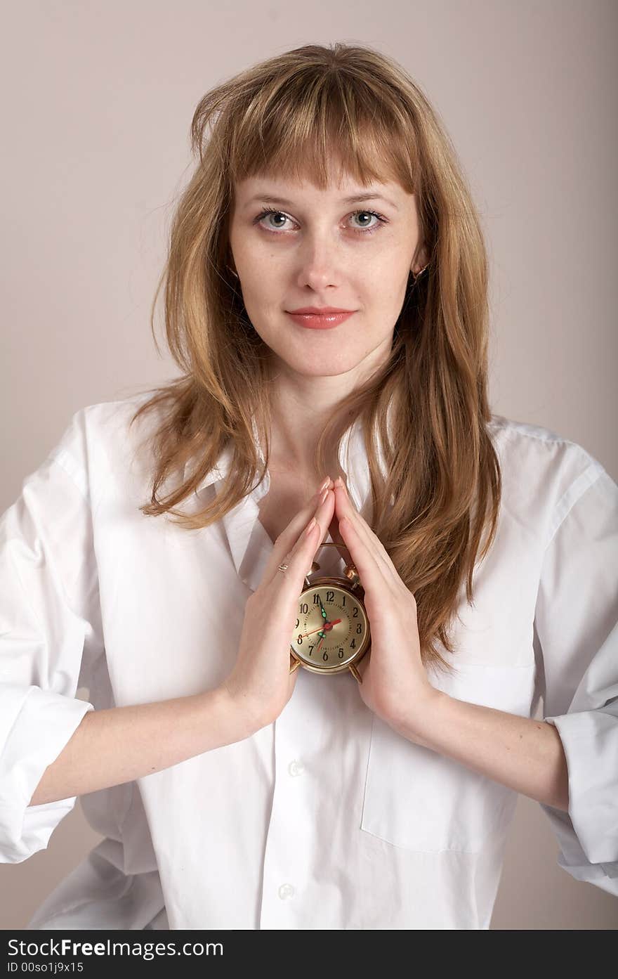 A nice girl in a shirt holding an alarm-clock. A nice girl in a shirt holding an alarm-clock