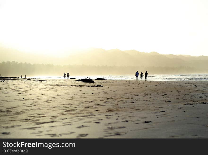 People walking on the beach by beautiful tropical sunset. People walking on the beach by beautiful tropical sunset