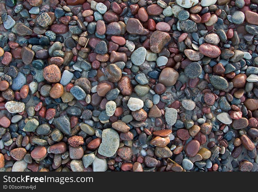 Wet sunlit beach pebbles background