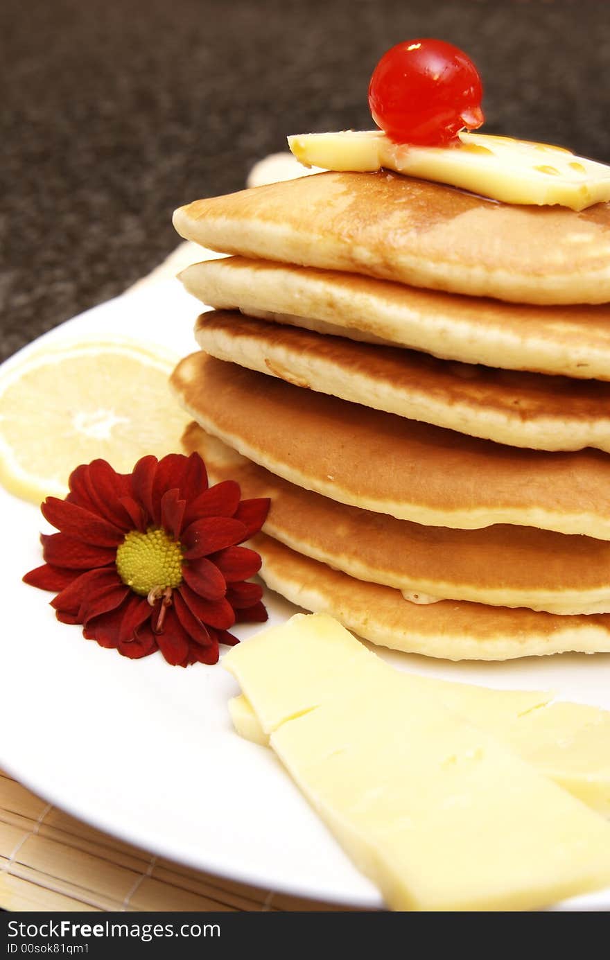 Stack of flapjacks with a red flower. A cherry is lying on top of the stack of flapjacks. Stack of flapjacks with a red flower. A cherry is lying on top of the stack of flapjacks