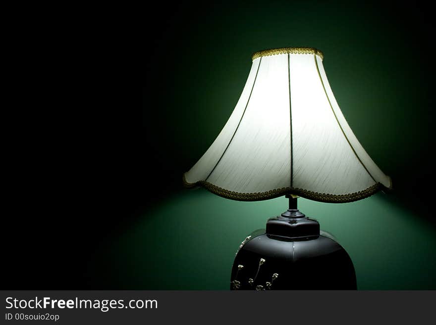 Styling table lamp turned on in a green painted room