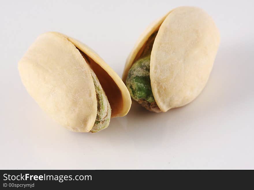 Two pistachio nuts seen up close on a white background.