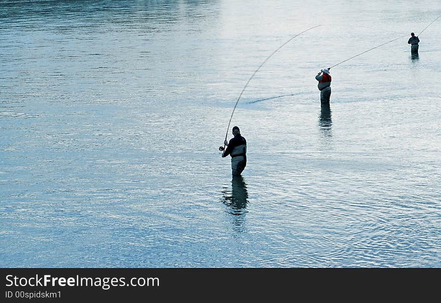 3 fishermen silhouetted against the river