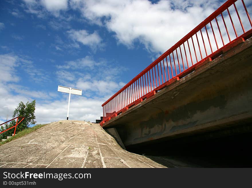 The bridge with a red handrail against the solar sky.