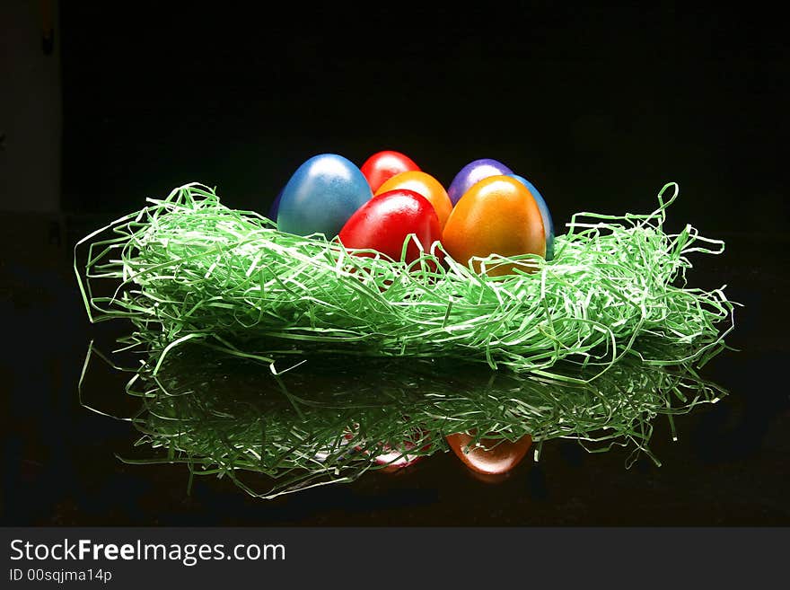 Colored eggs are standing with green on the black background. Colored eggs are standing with green on the black background