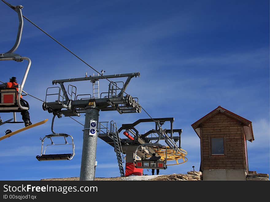 The arrival of a ski lift chairs with a blue sky on background. The arrival of a ski lift chairs with a blue sky on background