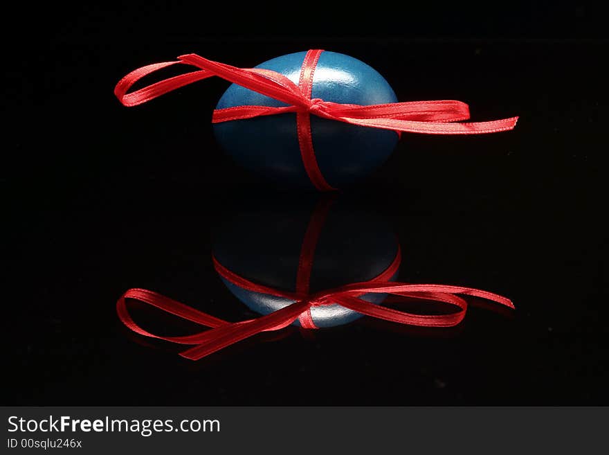 The blue Easter egg is standing with red bow