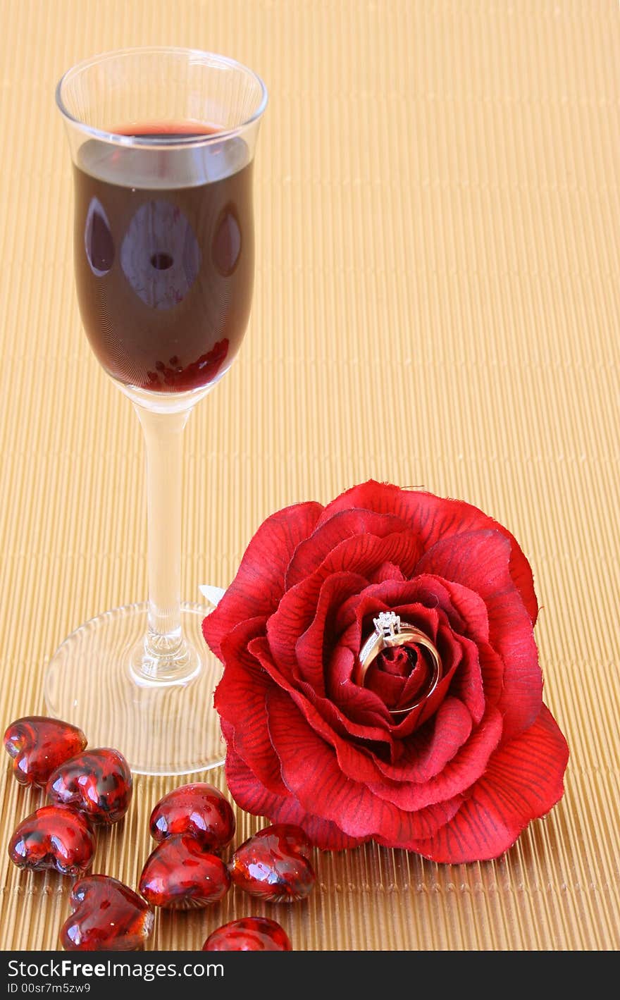 Small after-dinner wine glass with a red rose with a ring in it. Small after-dinner wine glass with a red rose with a ring in it