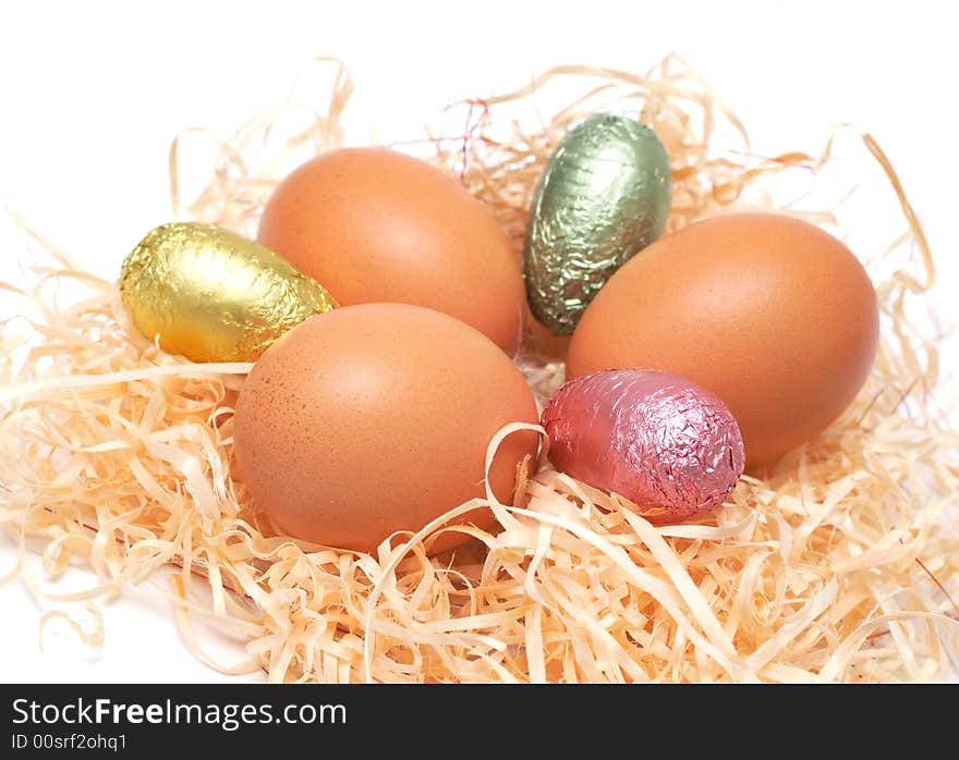 Real Easter and colorful chocolate eggs in straw on white background. Real Easter and colorful chocolate eggs in straw on white background