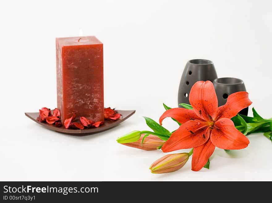 Red lily, red scented candle and black oil burner isolated on white background. Red lily, red scented candle and black oil burner isolated on white background.