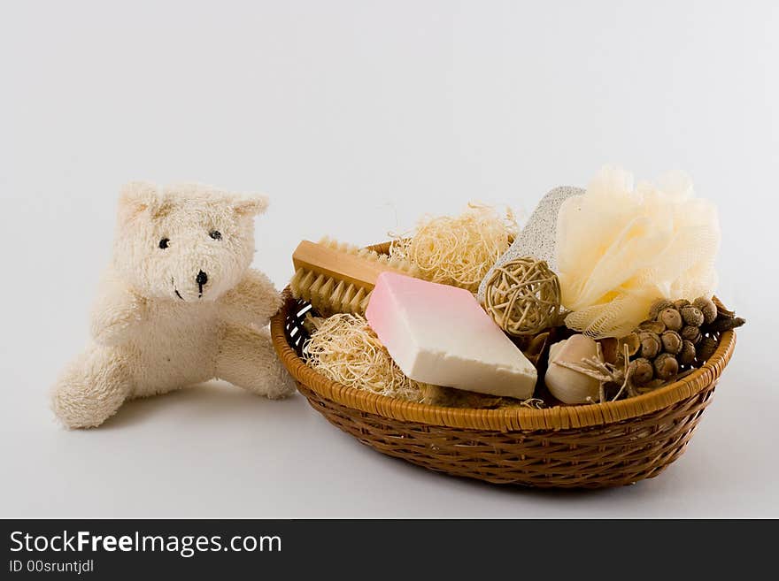 Teddy bear, personal care items and decorations in a basket isolated on white background.